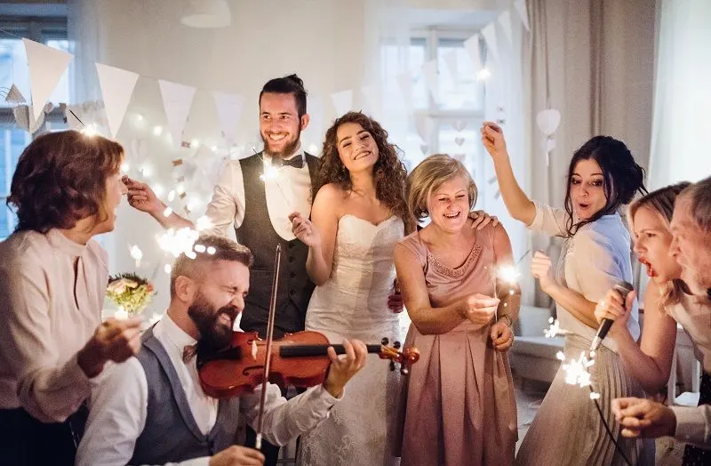 A young bride, groom and other guests dancing and singing on a wedding reception