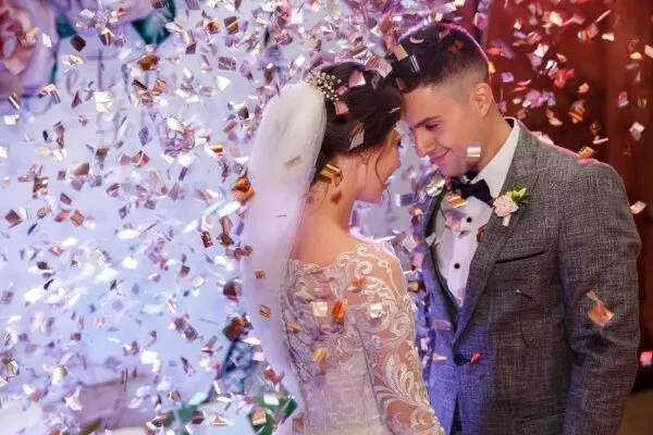 Happy-bride-and-groom-dancing-under-confetti-at-wedding-reception.-cm