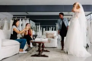 Woman trying on wedding dress in a shop with friends-cm (1)